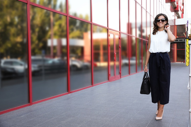 Photo of Young businesswoman near modern building on city street