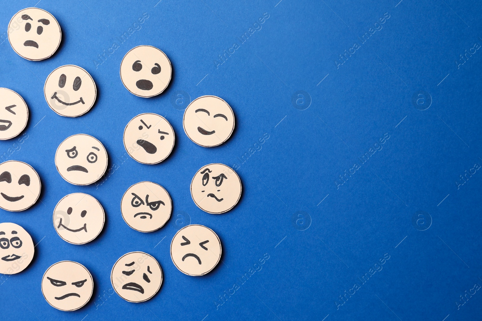 Photo of Many faces with different emotions on blue background, flat lay. Space for text