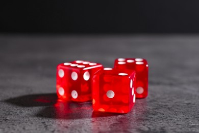Photo of Three red game dices on grey textured table, closeup. Space for text