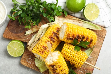 Tasty grilled corn cobs on light table, flat lay