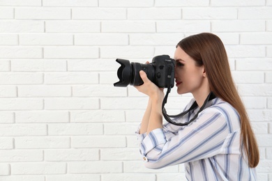 Photo of Professional photographer taking picture near white brick wall