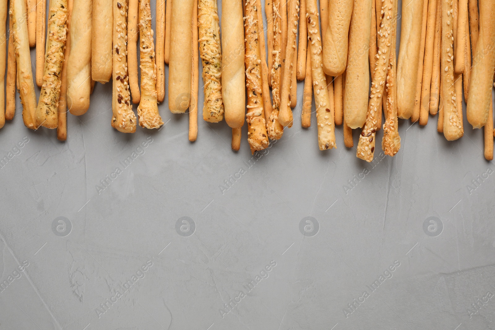 Photo of Delicious grissini sticks on light grey table, flat lay. Space for text