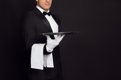 Photo of Butler with tray on black background, closeup. Space for text