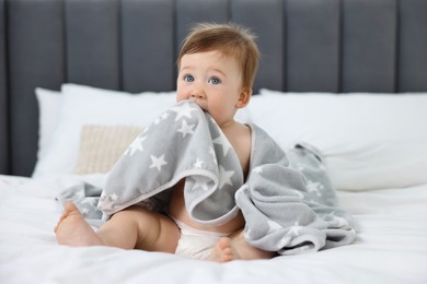 Photo of Cute baby boy with blanket sitting on bed at home