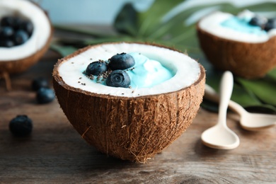 Photo of Coconut with spirulina smoothie on wooden table, closeup