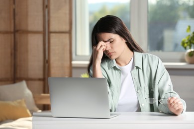Photo of Young woman suffering from eyestrain at desk in office