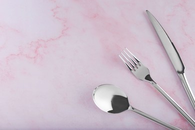 Photo of Stylish cutlery set on pink marble table, flat lay. Space for text