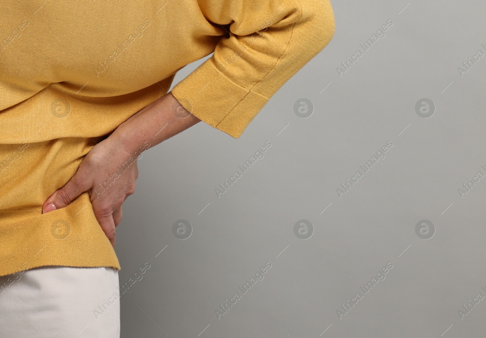 Photo of Arthritis symptoms. Woman suffering from back pain on gray background