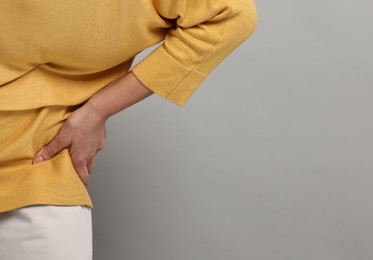 Photo of Arthritis symptoms. Woman suffering from back pain on gray background