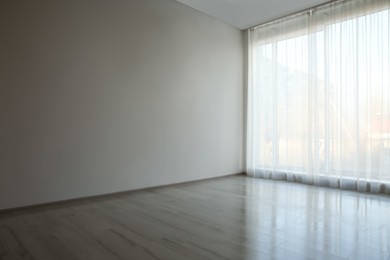 Photo of Empty room with white wall, large window and wooden floor