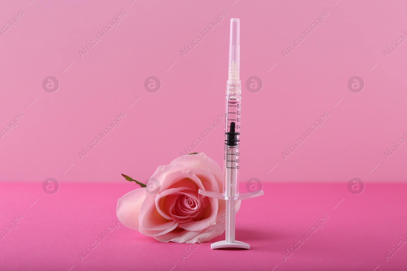 Photo of Cosmetology. Medical syringe and rose flower on pink background