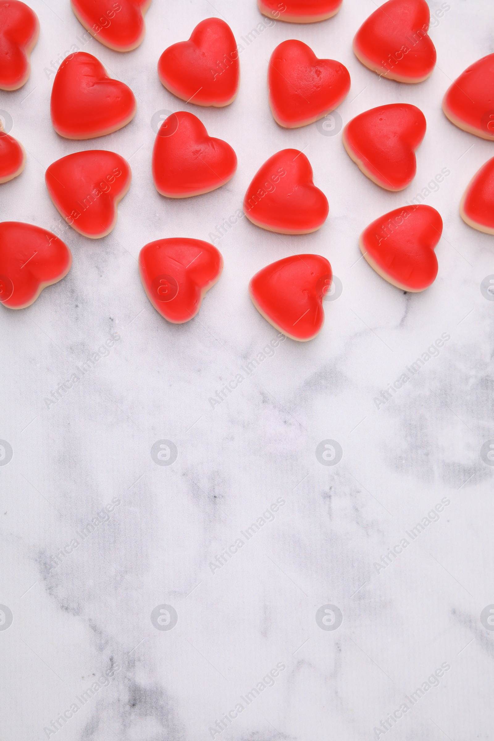 Photo of Delicious heart shaped jelly candies on white marble table, flat lay. Space for text