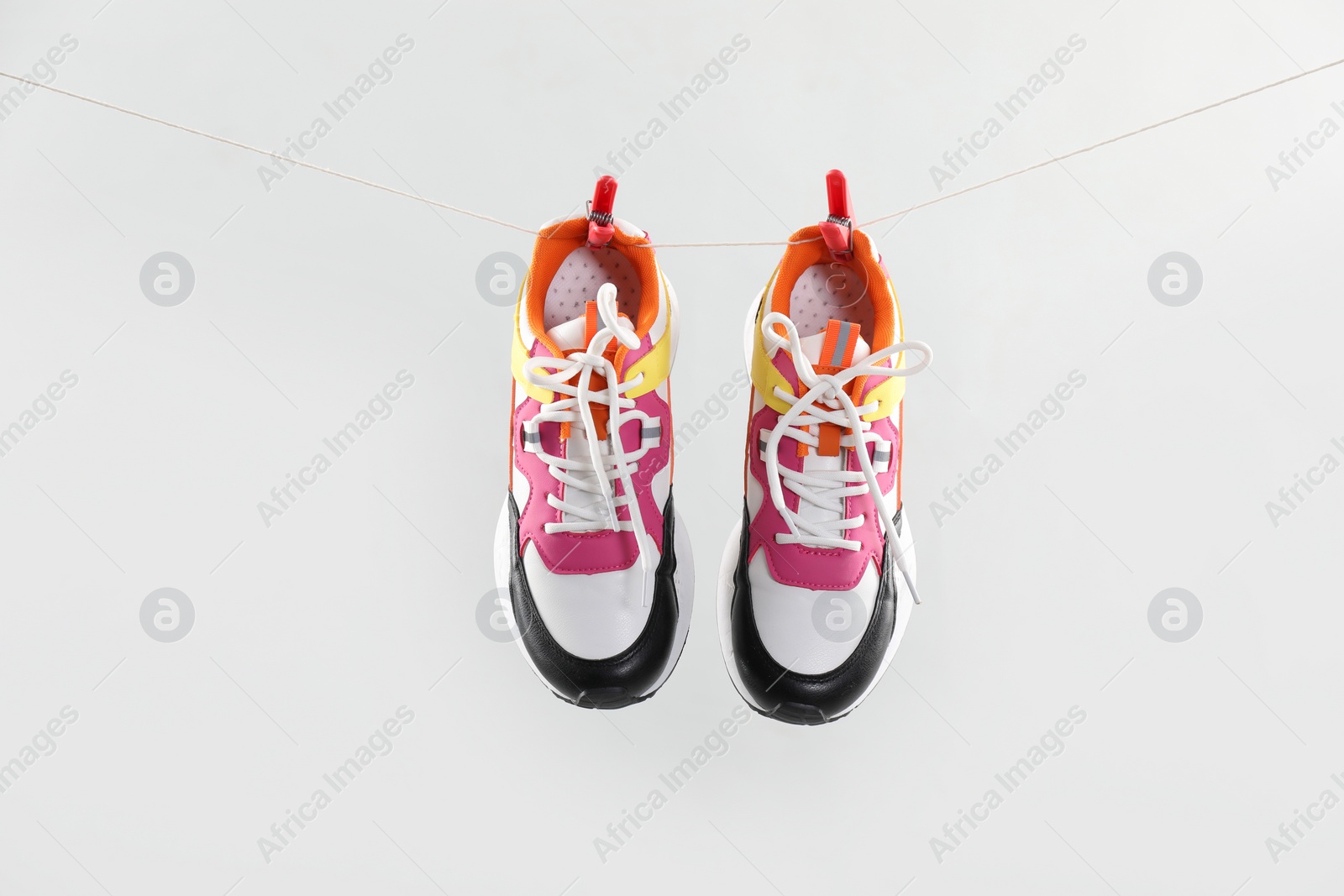 Photo of Stylish sneakers drying on washing line against light grey background