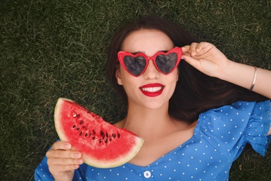 Photo of Beautiful young woman with watermelon on green grass outdoors, top view