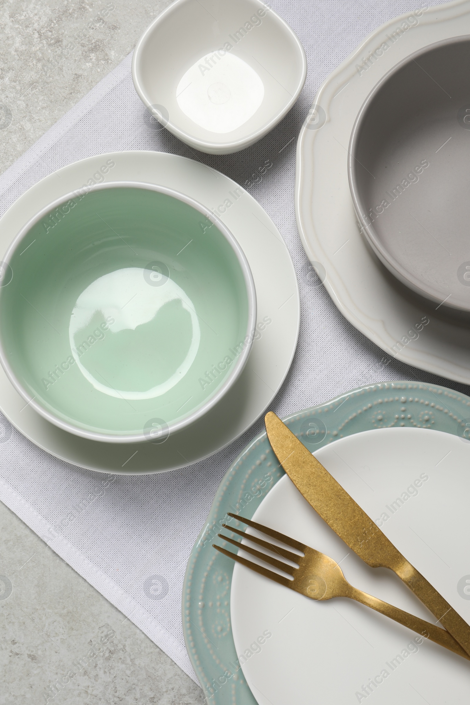 Photo of Beautiful ceramic dishware and cutlery on light grey table, top view