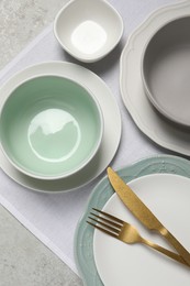 Beautiful ceramic dishware and cutlery on light grey table, top view