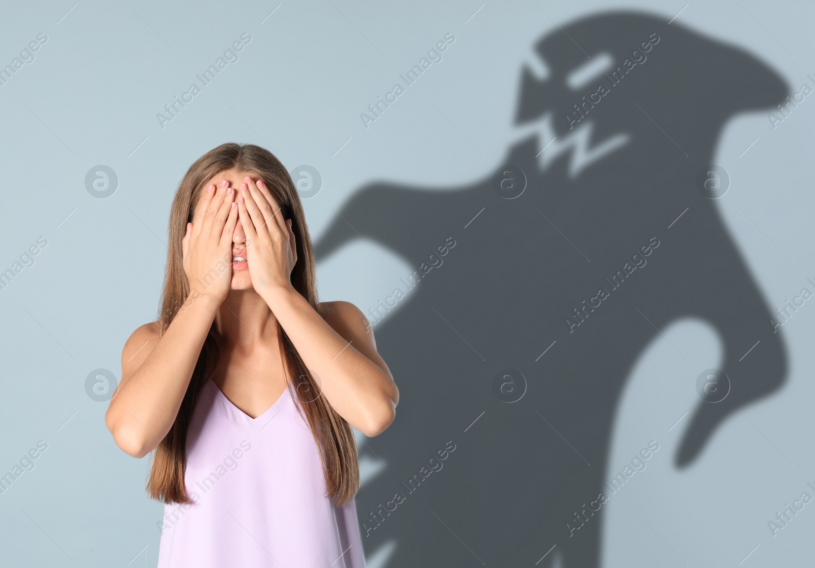 Image of Young woman suffering from sciophobia and phantom behind her. Irrational fear of shadows