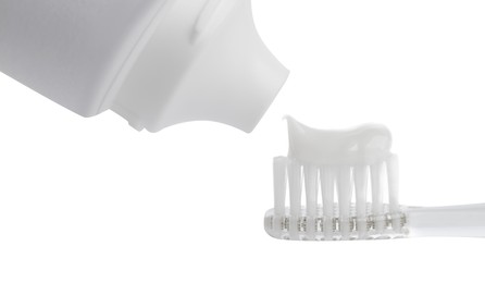 Applying paste on electric toothbrush against white background, closeup