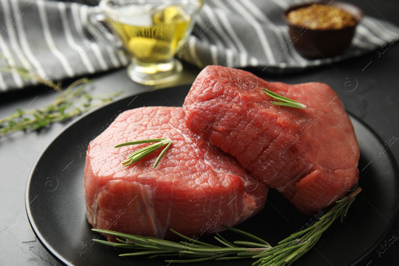 Photo of Fresh raw beef cut with rosemary on table, closeup