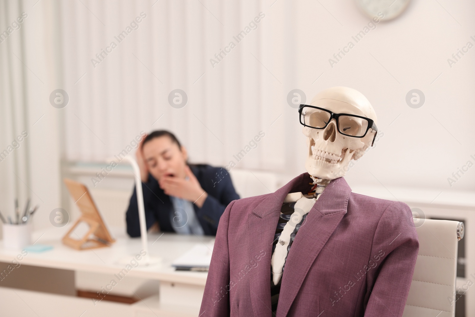 Photo of Human skeleton with suit and glasses in office. Space for text