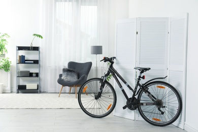 Photo of New bicycle near folding screen in stylish room interior