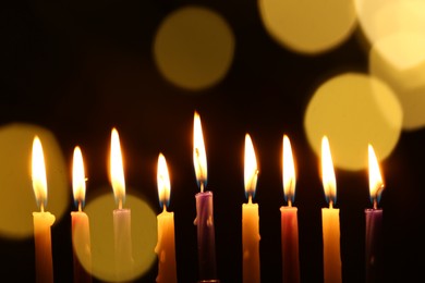 Photo of Hanukkah celebration. Burning candles on dark background with blurred lights