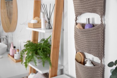 Knitted organizer hanging on wall in bathroom