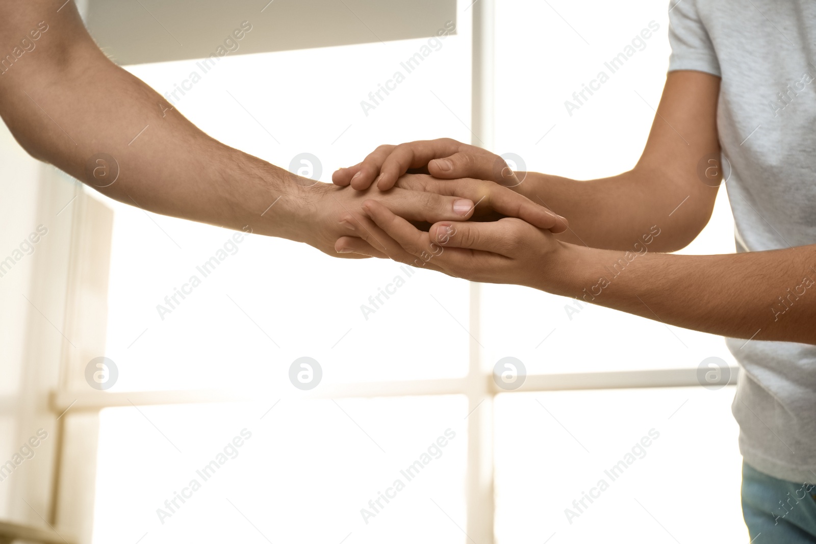 Photo of Young people holding hands indoors, closeup. Happy family