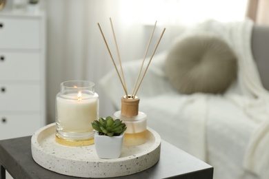 Photo of Air reed freshener, candle and plant on table in room, space for text