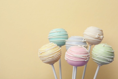 Sweet colorful cake pops on yellow background