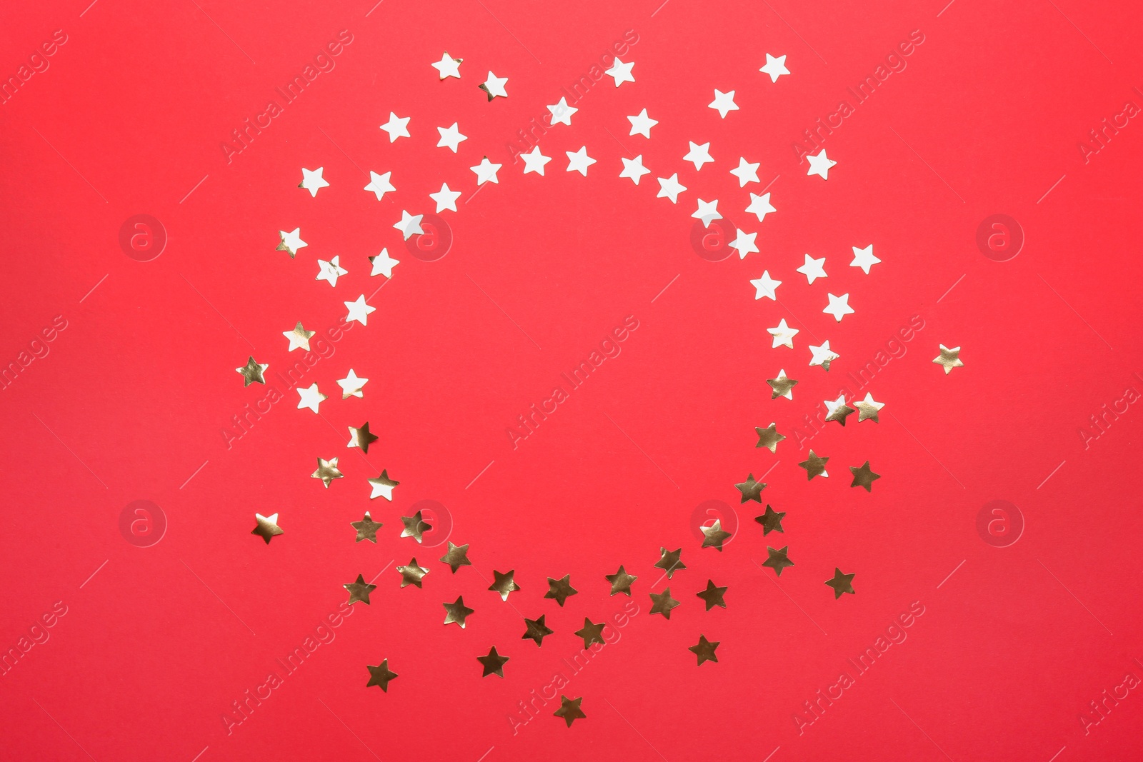 Photo of Frame made of confetti stars with space for text on red background, top view. Christmas celebration