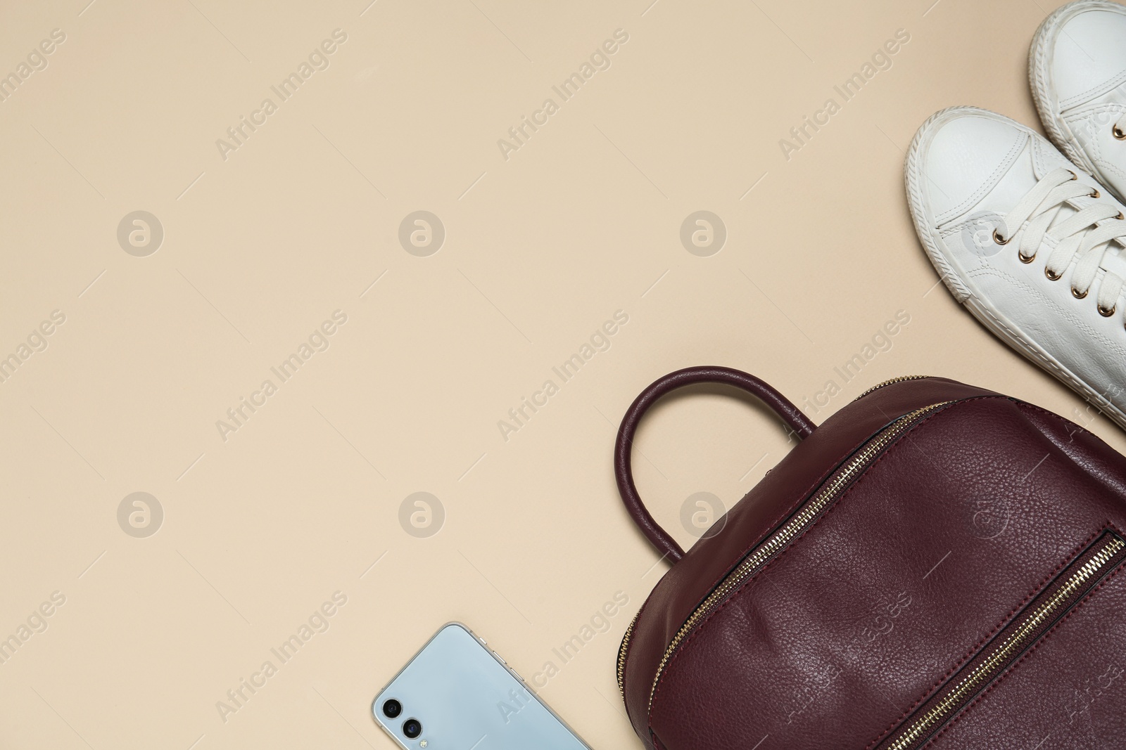 Photo of Stylish casual backpack, smartphone and sneakers on beige background, flat lay. Space for text