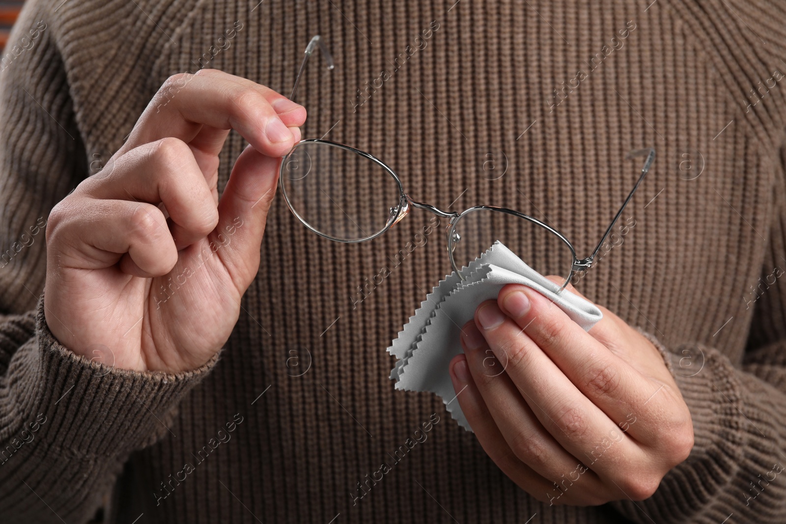 Photo of Man wiping glasses with microfiber cloth, closeup