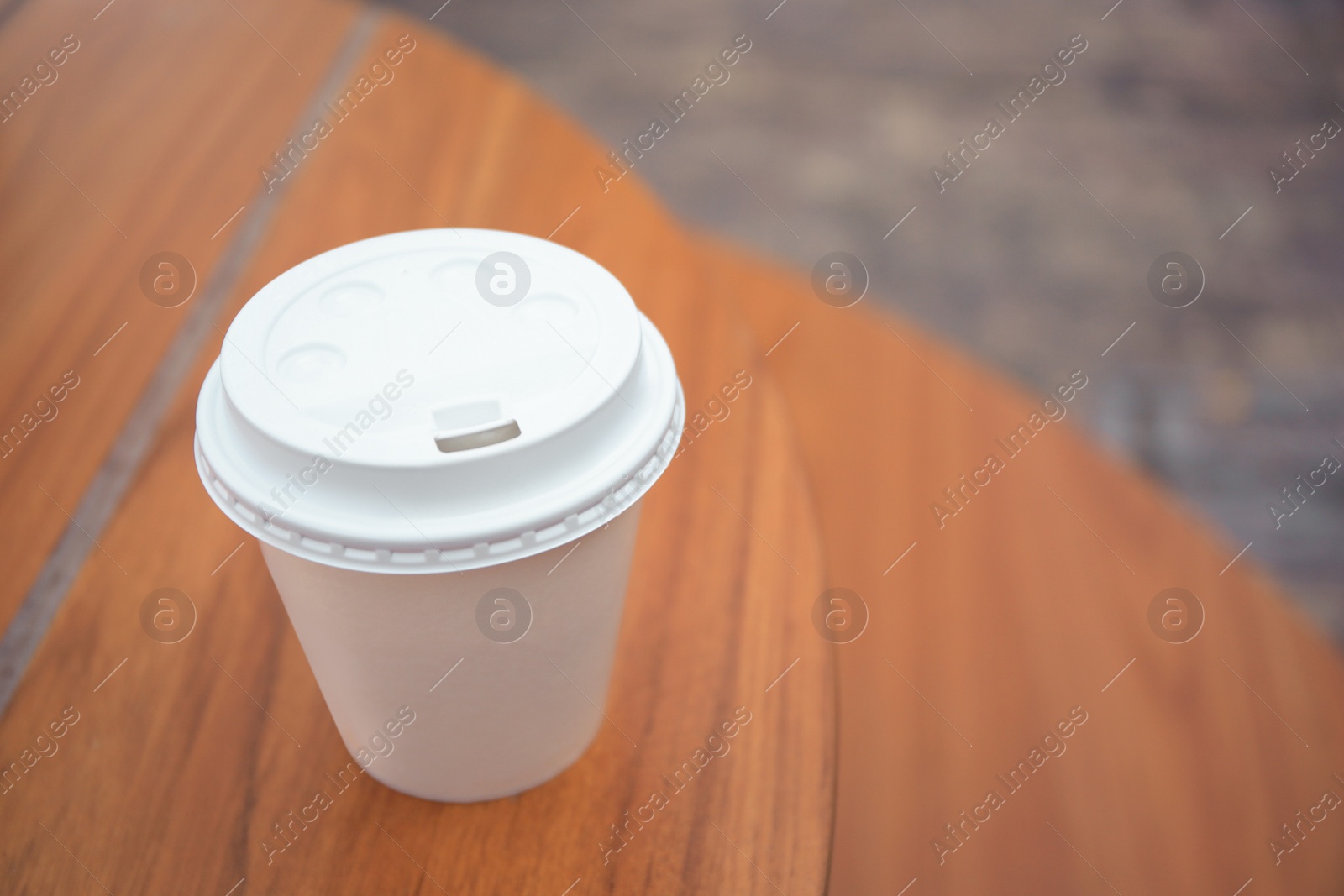 Photo of Cardboard cup with tasty coffee on table outdoors, closeup. Space for text