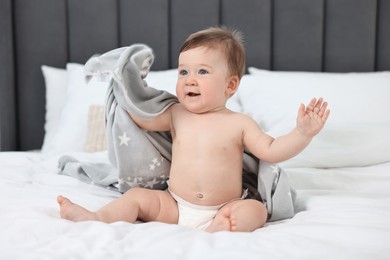 Cute baby boy sitting on bed at home