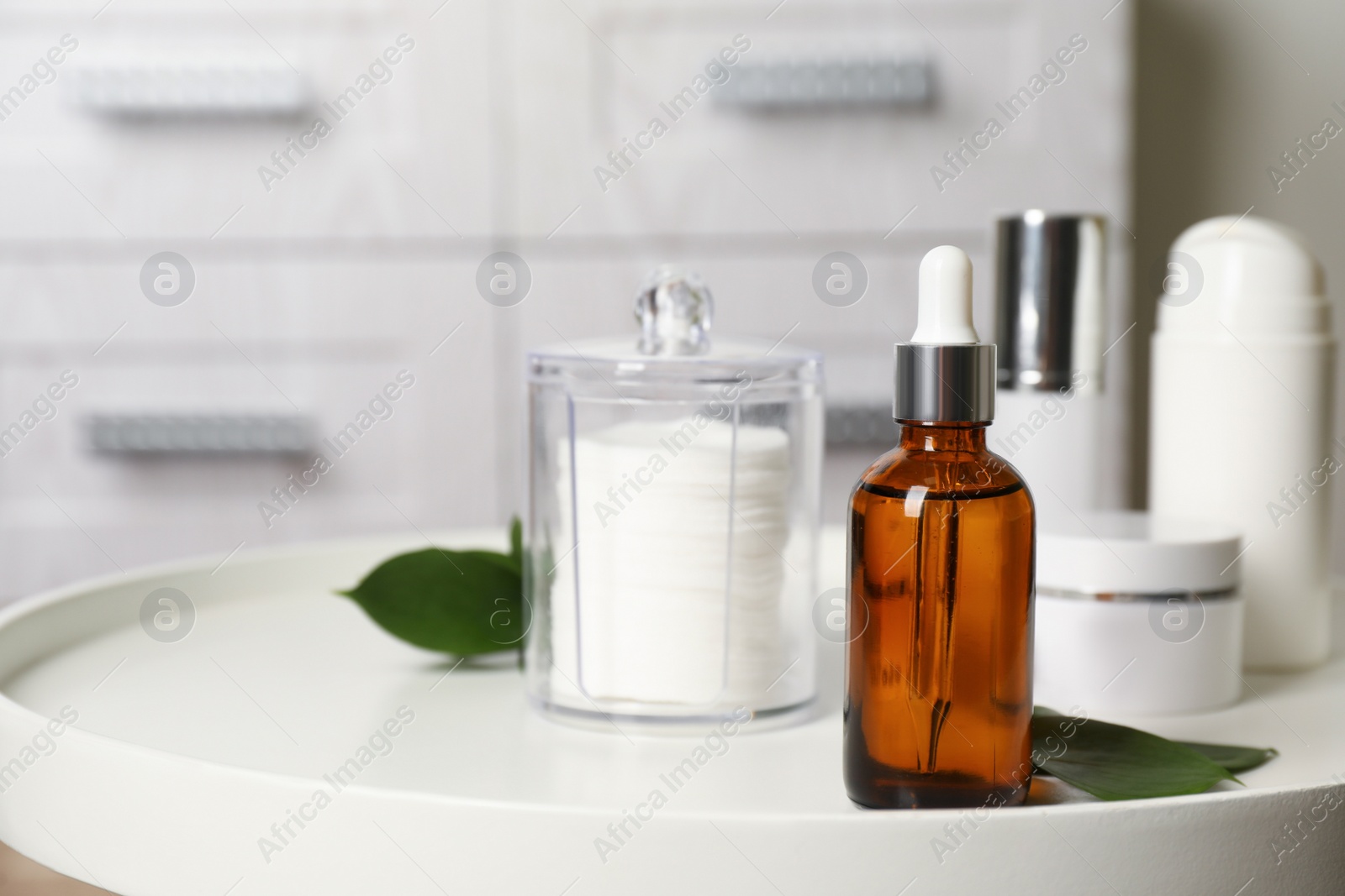 Photo of Makeup removal product and leaves on white table in bathroom