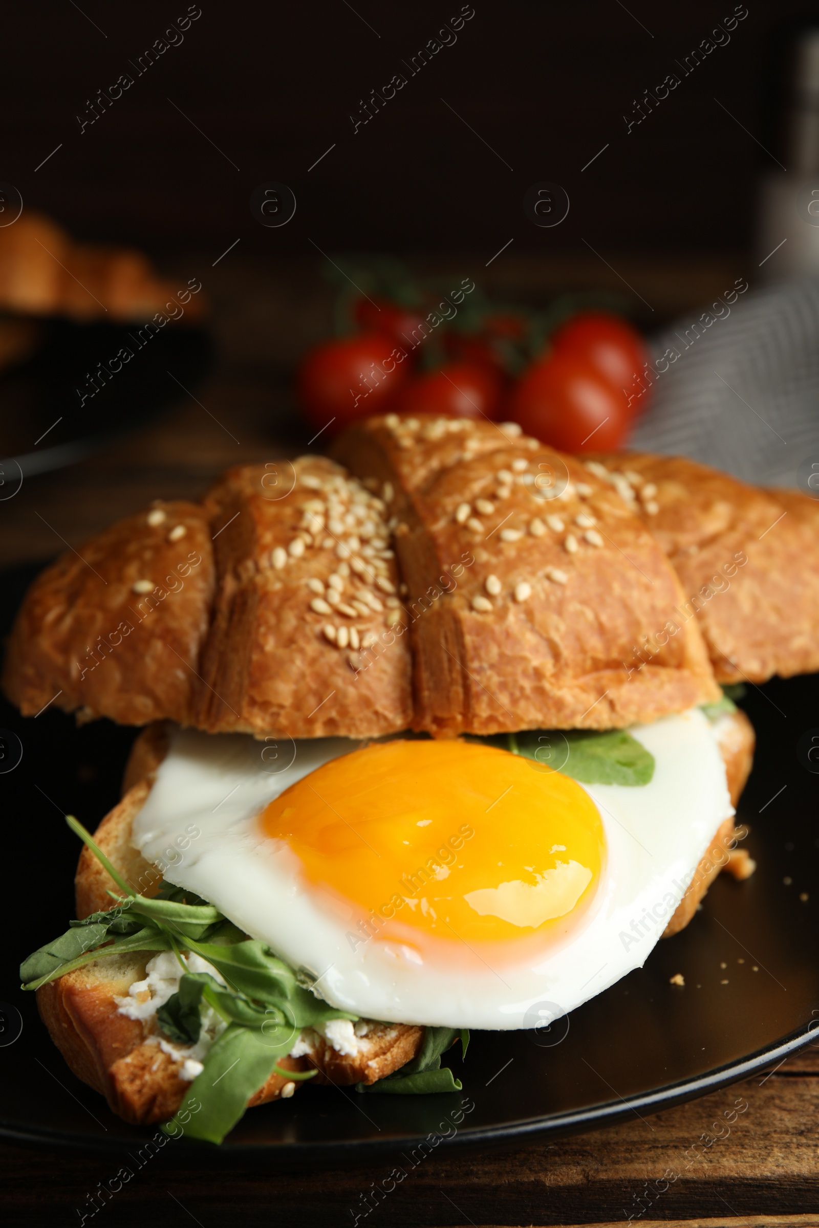 Photo of Delicious croissant with arugula and fried egg on wooden table, closeup