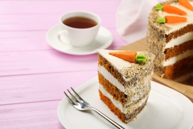 Photo of Sweet carrot cake with delicious cream on pink wooden table, space for text