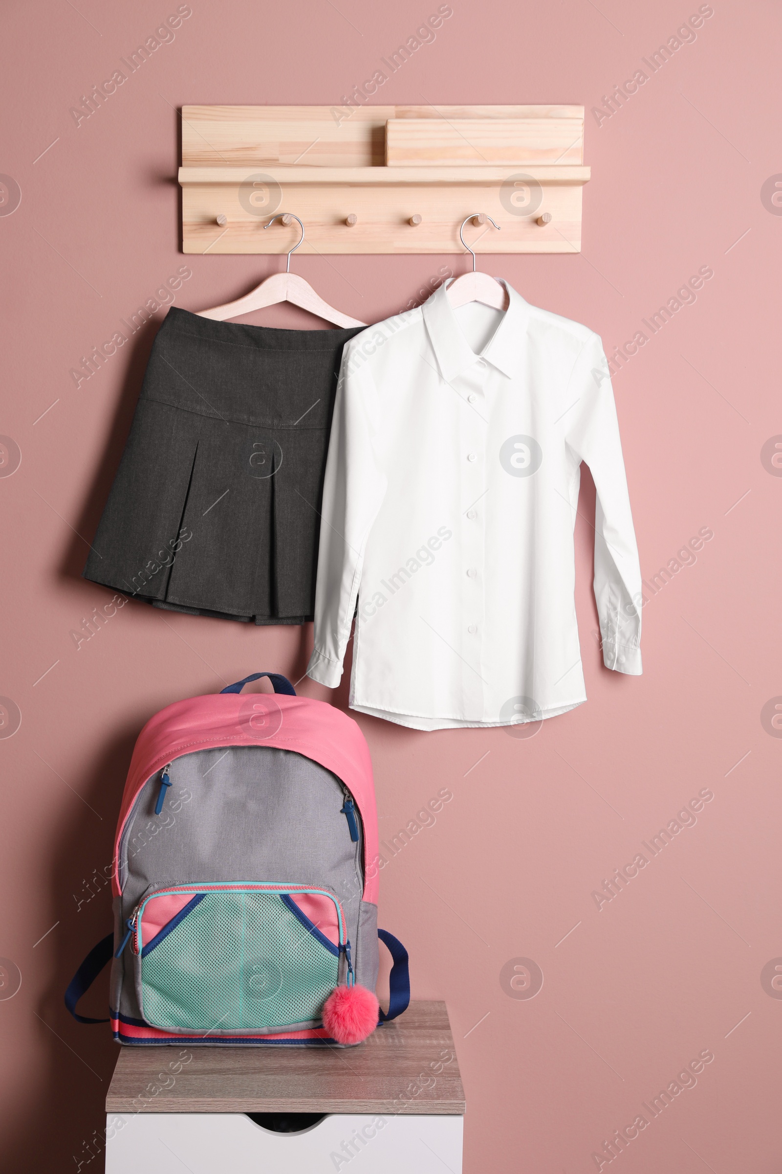 Photo of School uniform for girl and backpack near beige wall
