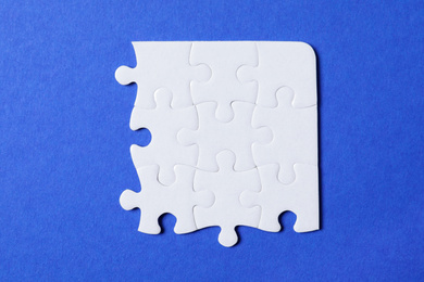Photo of Blank white puzzle pieces on blue background, flat lay