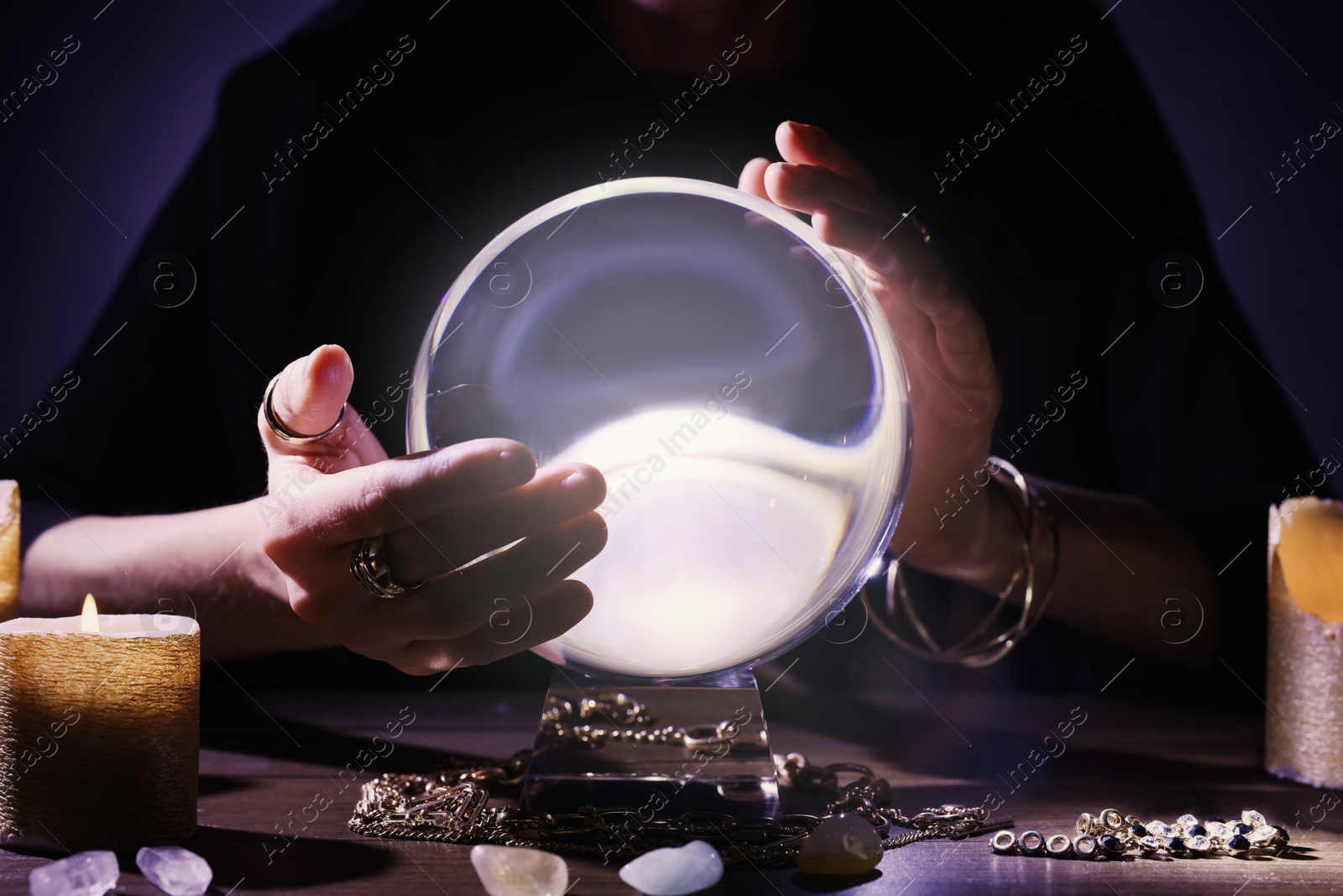 Photo of Soothsayer using crystal ball to predict future at table in darkness, closeup. Fortune telling