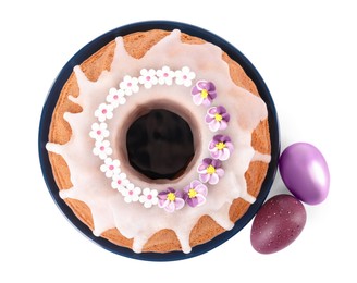 Photo of Festively decorated Easter cake and painted eggs on white background, top view