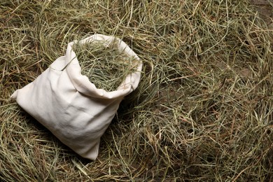 Photo of Dried hay in burlap sack on wooden table, top view. Space for text