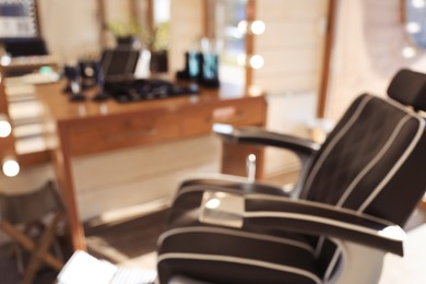 Photo of Blurred view of stylish barber chair near mirror in hairdressing salon