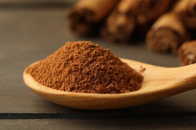 Photo of Spoon with cinnamon powder on wooden table, closeup