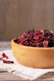 Photo of Dry hibiscus tea in bowl on table, closeup