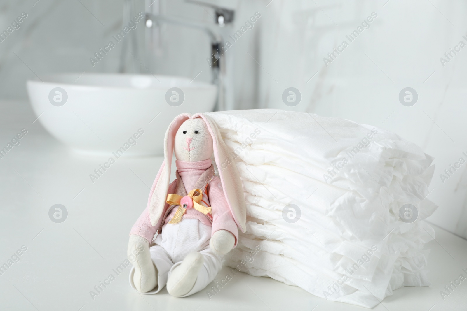 Photo of Stack of baby diapers and toy bunny on counter in bathroom