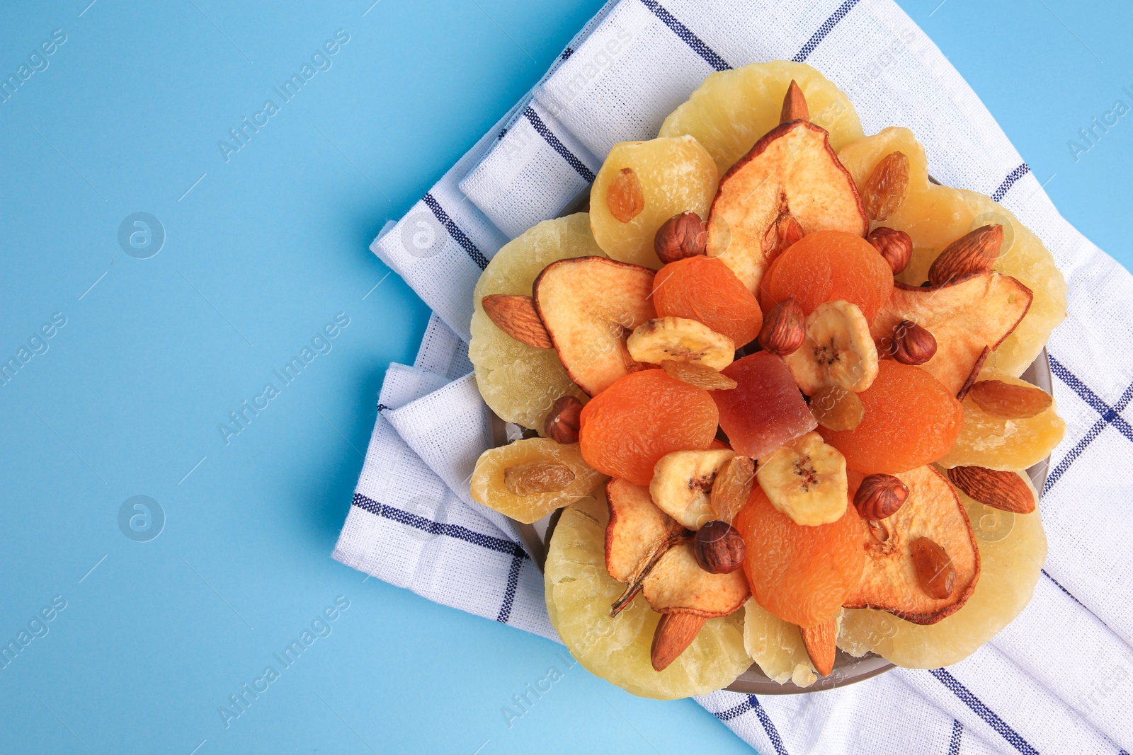 Photo of Mixed dried fruits and nuts on light blue background, top view. Space for text