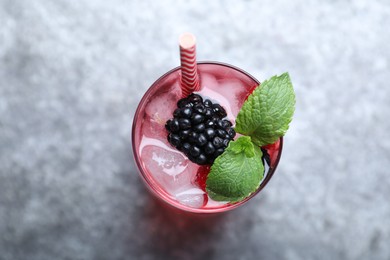 Photo of Delicious strawberry lemonade with soda water, mint and blackberries on grey table, top view. Fresh summer cocktail