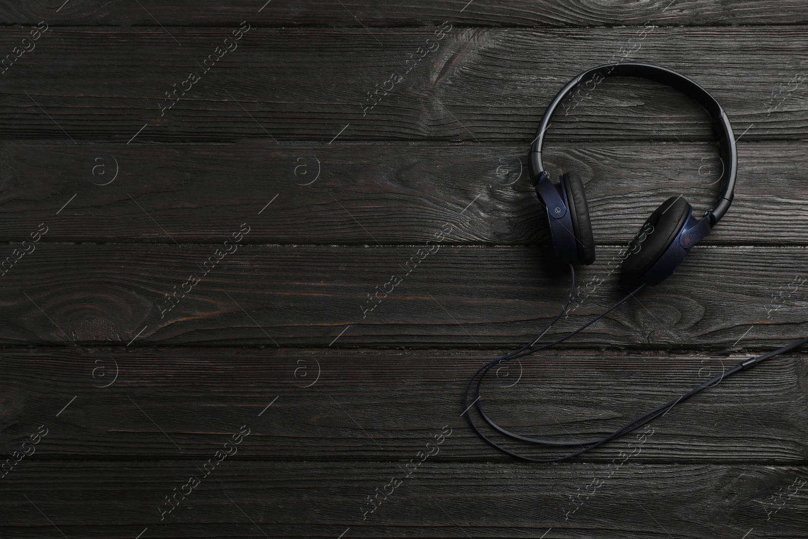 Photo of Stylish modern headphones and space for text on wooden background, top view